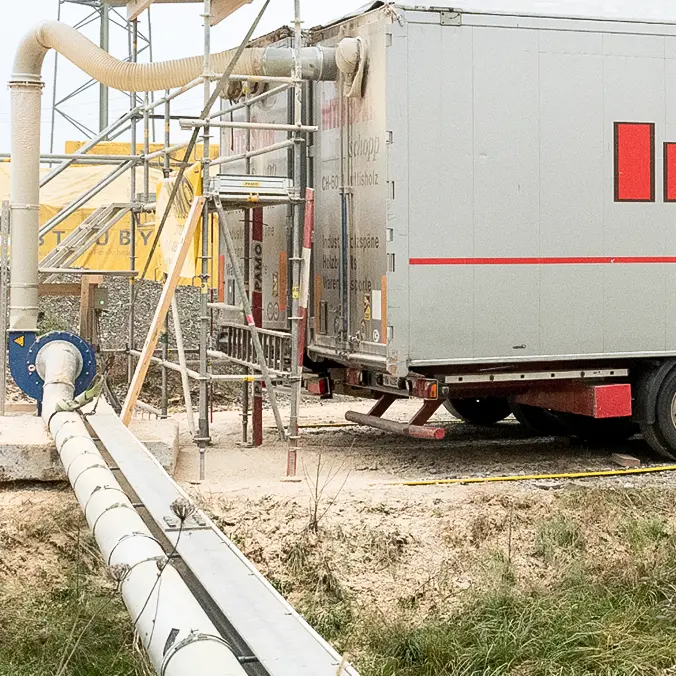 Remplissage de semi-remorques fermées (95 m3) avec de la poussière et des copeaux de bois dans un environnement difficile.